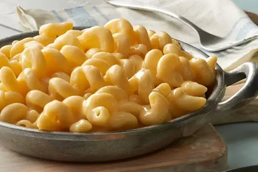 Creamy macaroni and cheese served in a rustic metal skillet, featuring tender elbow pasta coated in rich melted cheese sauce.