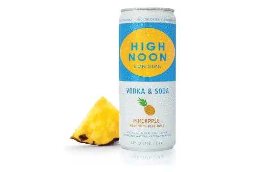 High Noon Pineapple Vodka & Soda can with condensation, displayed alongside a fresh pineapple slice on a clean white background