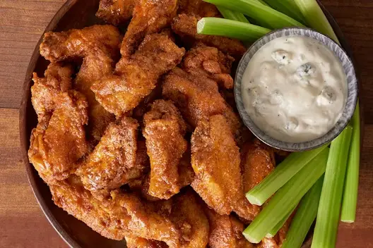 Kookaburra Wings® Party Platter featuring crispy seasoned chicken wings served with fresh celery sticks and a side of creamy blue cheese dressing.