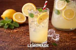 Fresh lemonade served over ice in a tall glass with lemon slices and mint, refreshing citrus drink