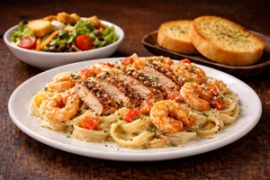 Pasta Bundle featuring creamy Cajun chicken and shrimp fettuccine topped with parmesan, served with fresh salad and garlic bread