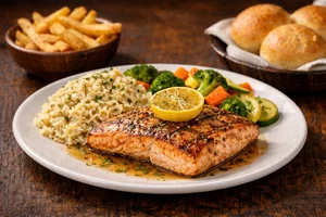Salmon Bundle featuring a perfectly grilled salmon fillet topped with lemon butter, served with rice, vegetables, fries, and warm dinner rolls
