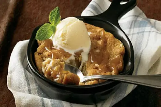 Salted caramel cookie skillet served warm in a cast-iron pan, topped with vanilla ice cream and fresh mint.